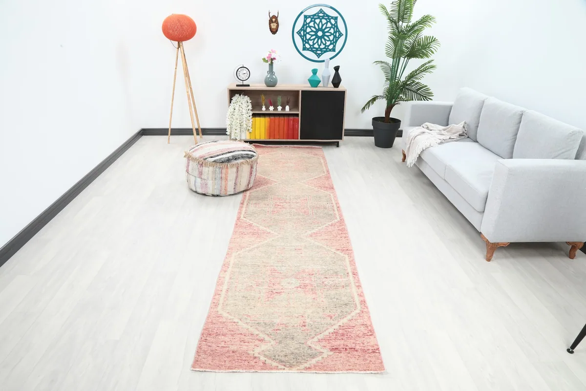 Vintage Anatolian runner rug with rose and gray geometric pattern in a modern living room setting.