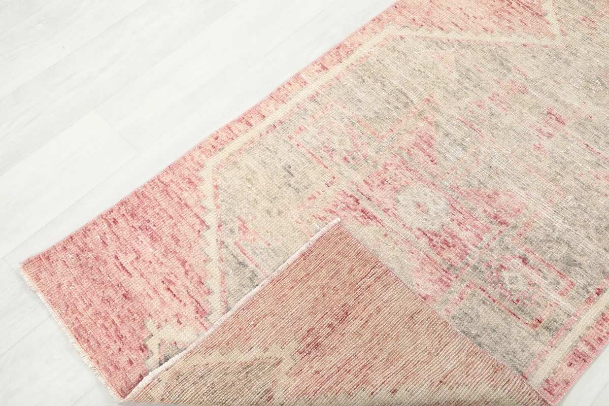 Folded corner of the vintage runner rug, showing the reverse side and the hand-knotted construction.