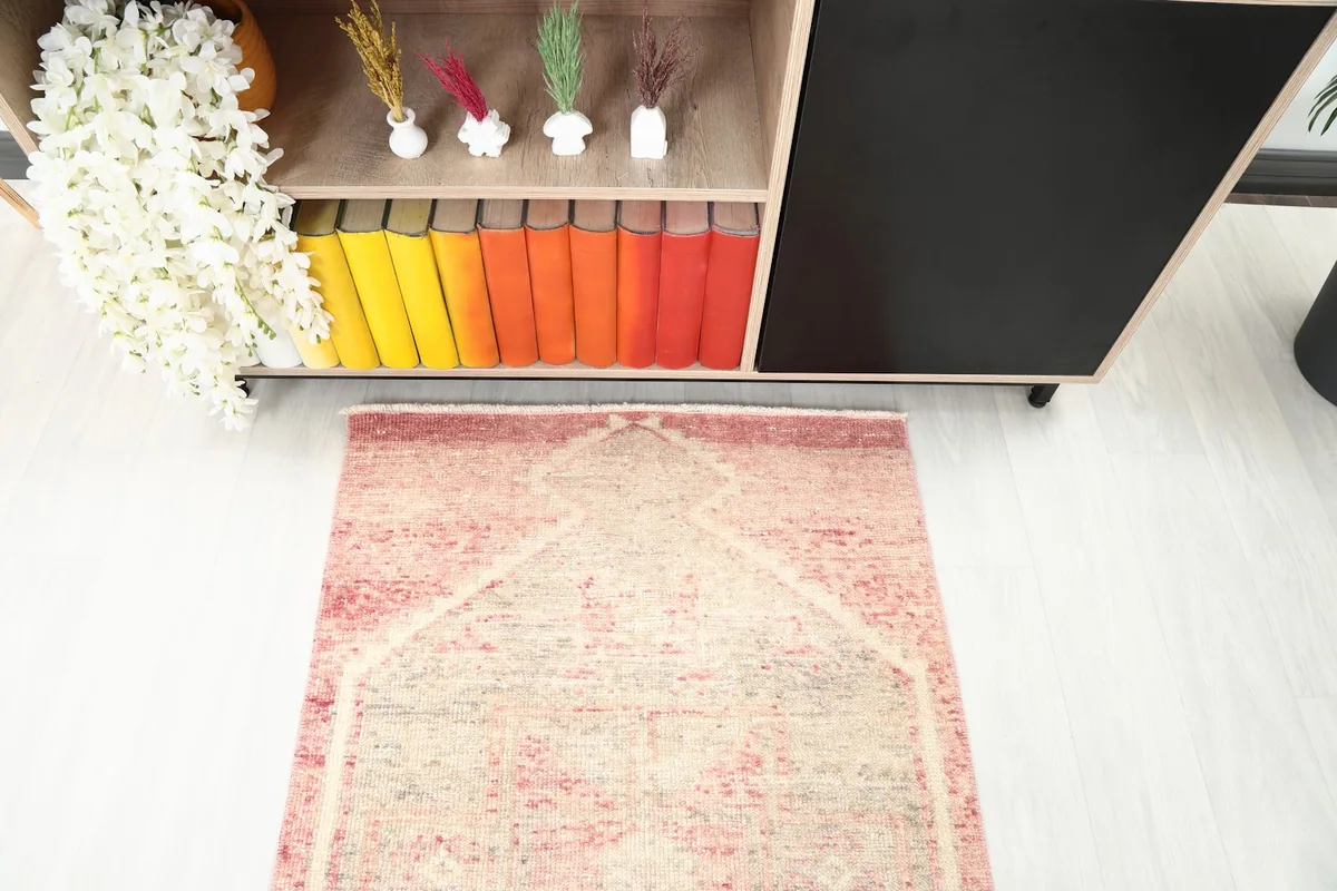 Overhead view of one end of the rose and gray runner rug, showing the geometric design and texture.