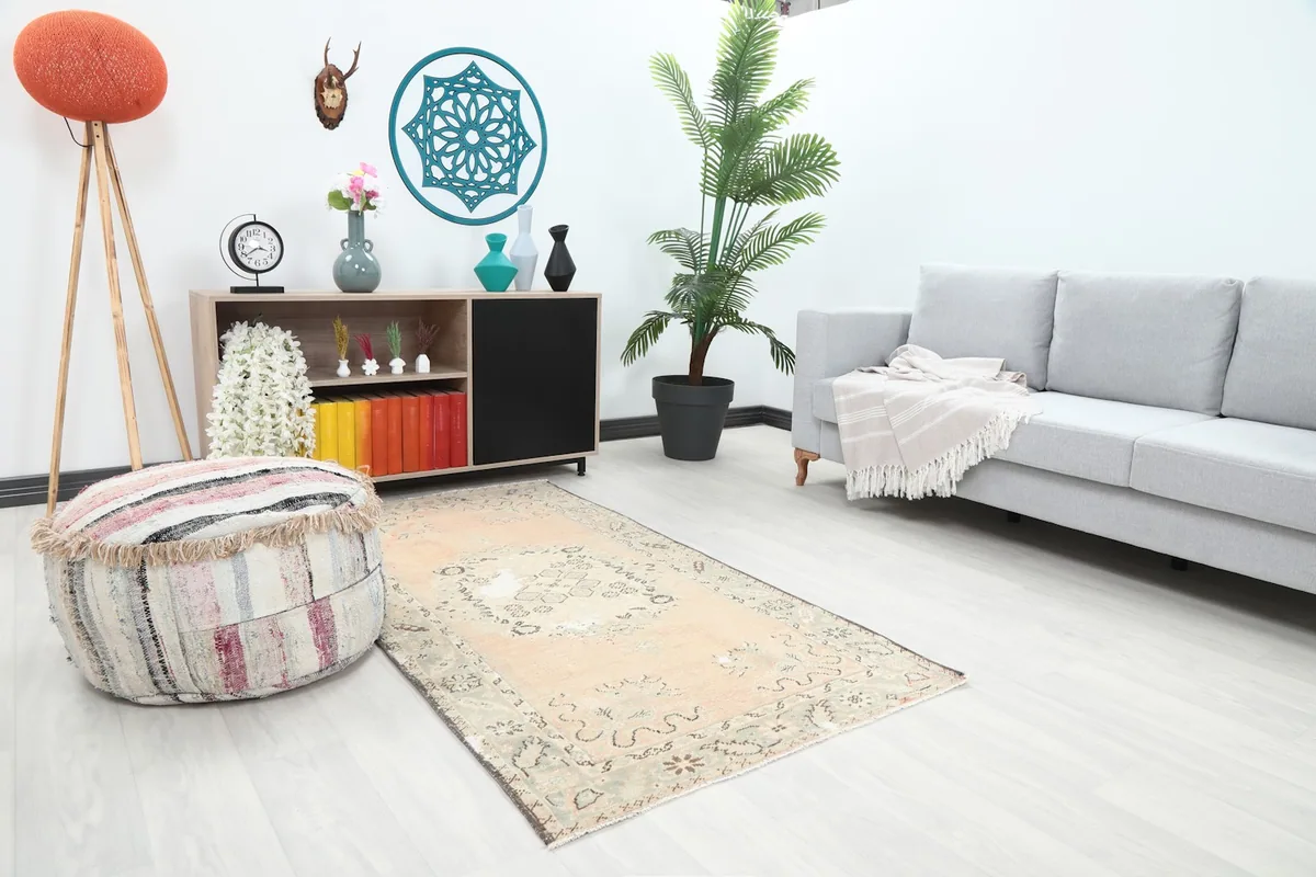 Angle view of the rose and gray rug placed in a living room, showing its size relative to a sofa.