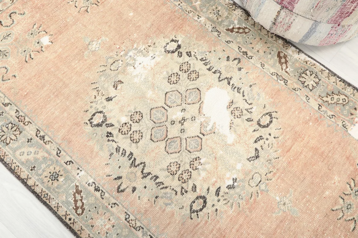 Close-up detail of the rug's central medallion, showing geometric patterns and areas of authentic wear.