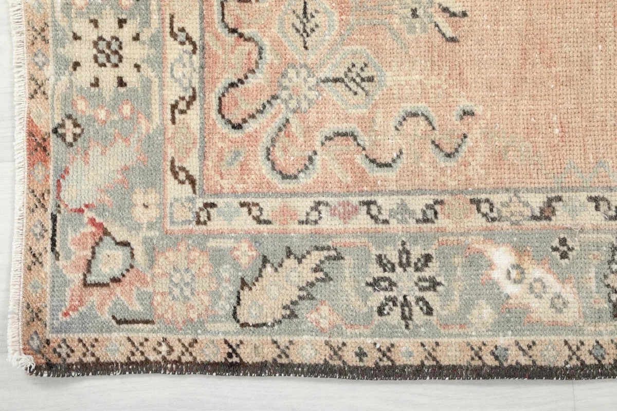 Close-up of the rug's gray and beige border, showcasing its patterned design and the transition to the rose field.