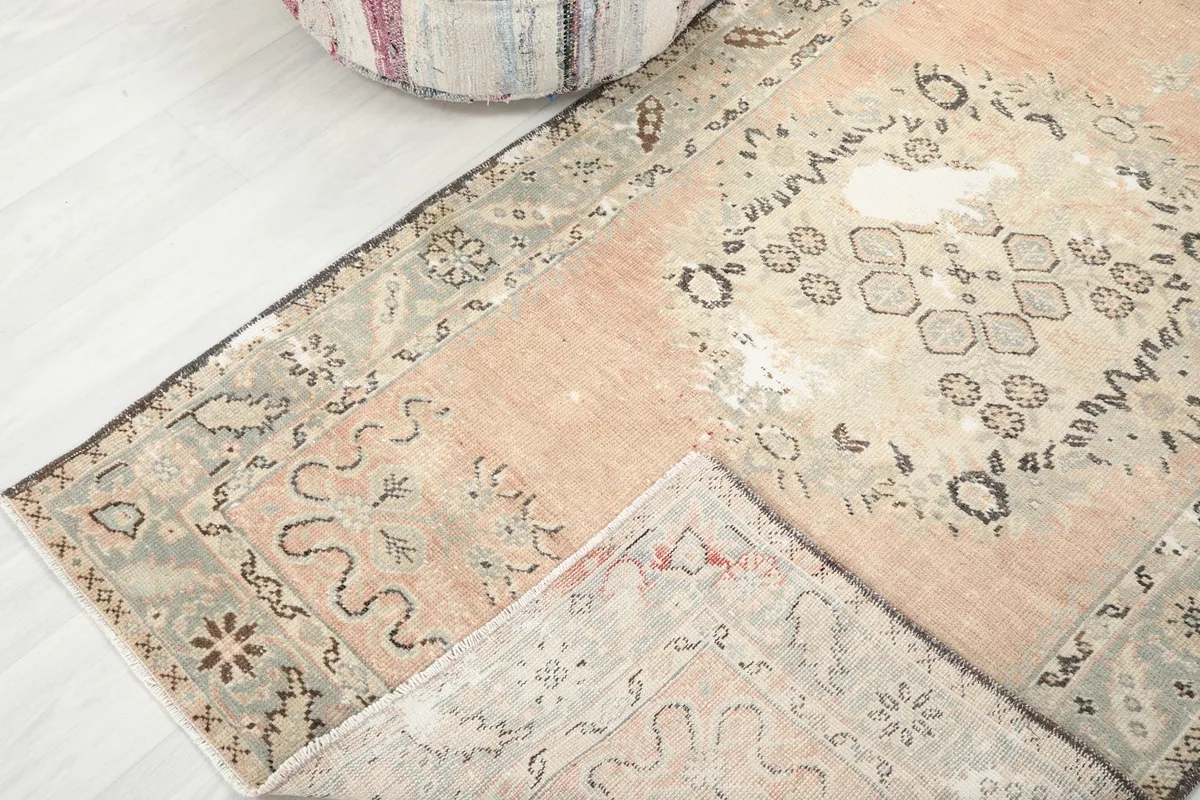 View of the rug's corner folded back to show the cotton foundation and hand-knotted construction.