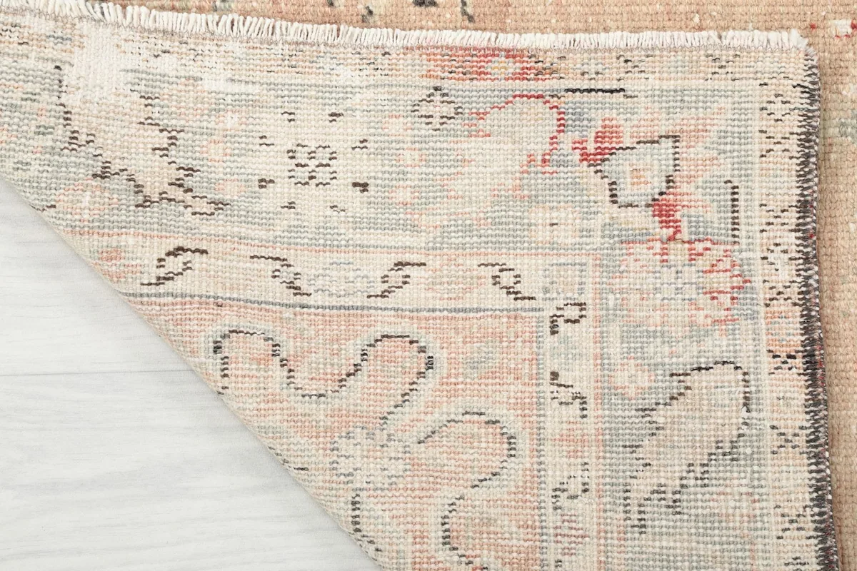 Another view of the rug's corner folded, displaying the reverse side of the hand-knotted wool pile and foundation.