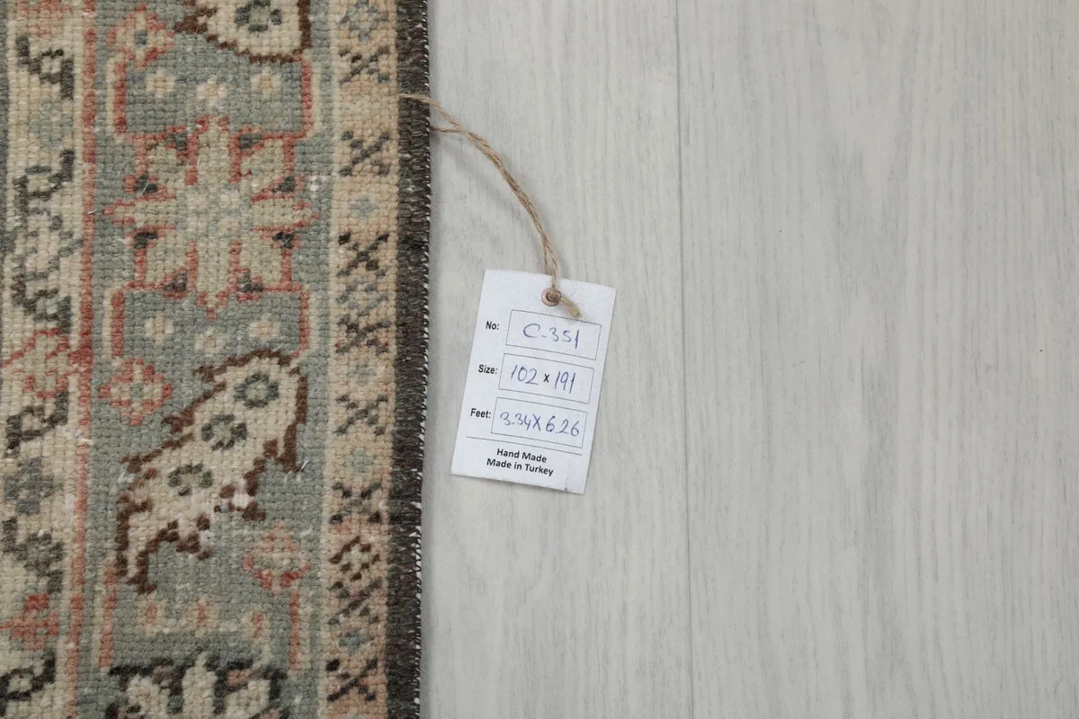 Close-up of the rug's identification tag, showing the dimensions 102x191 cm and origin.
