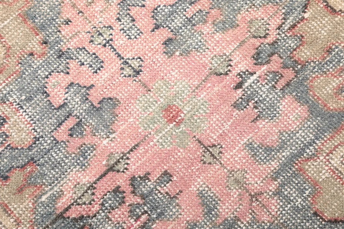 Close-up of the low wool pile, showing texture and color variations of the vintage rug