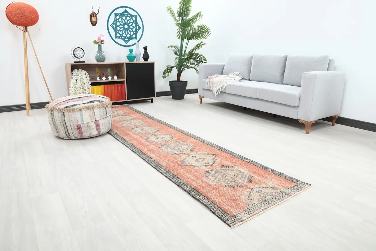 Runner rug in a hallway with a striped pouf and gray sofa, showing overall length