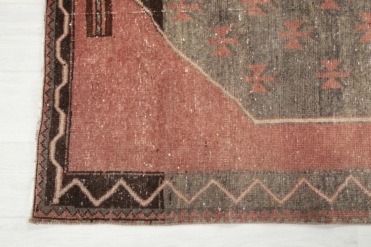 Close-up of the rug's border and corner, revealing the zigzag pattern and wool texture.
