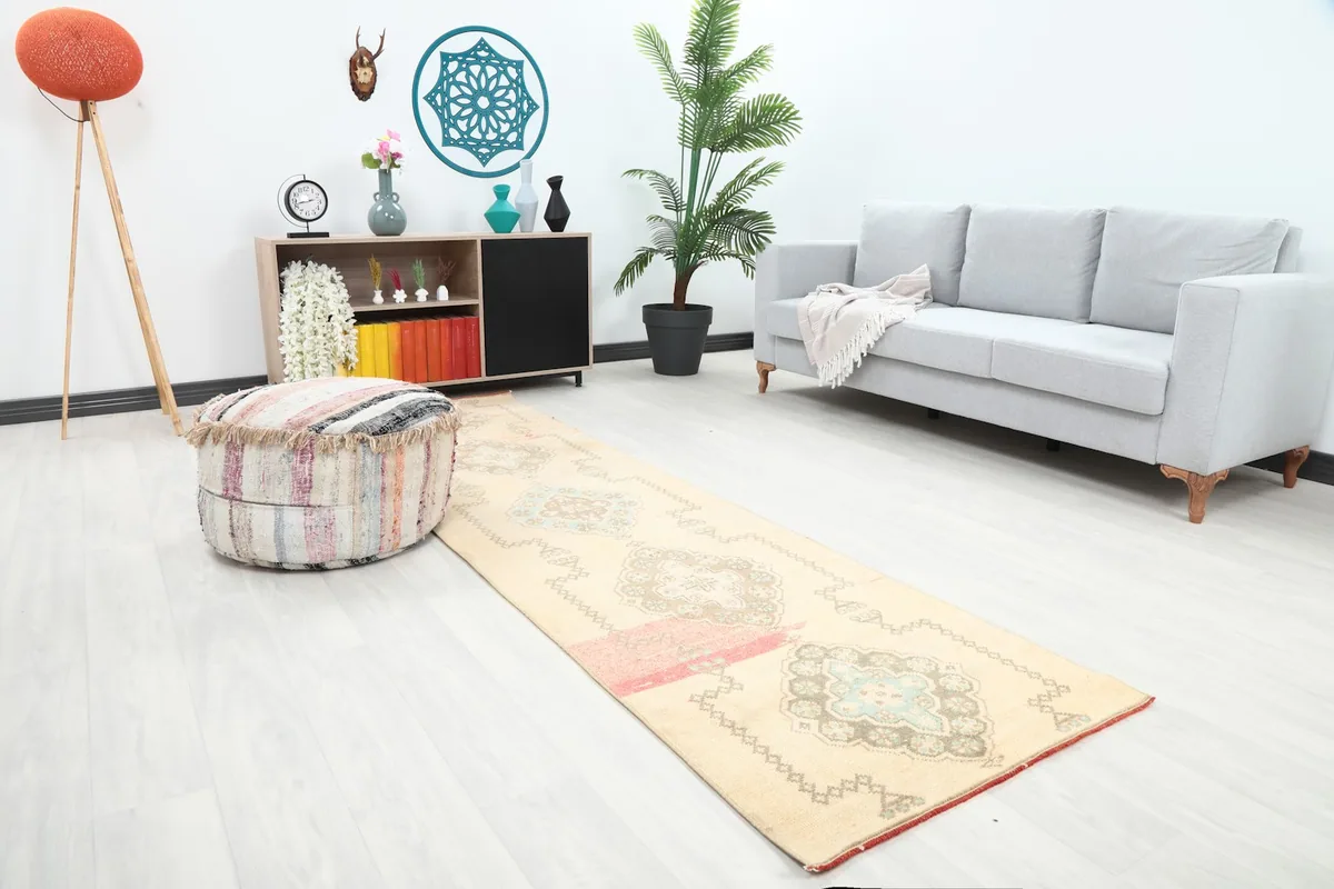 Angle view of the ivory runner rug in a room, showing its length and placement next to a sofa.