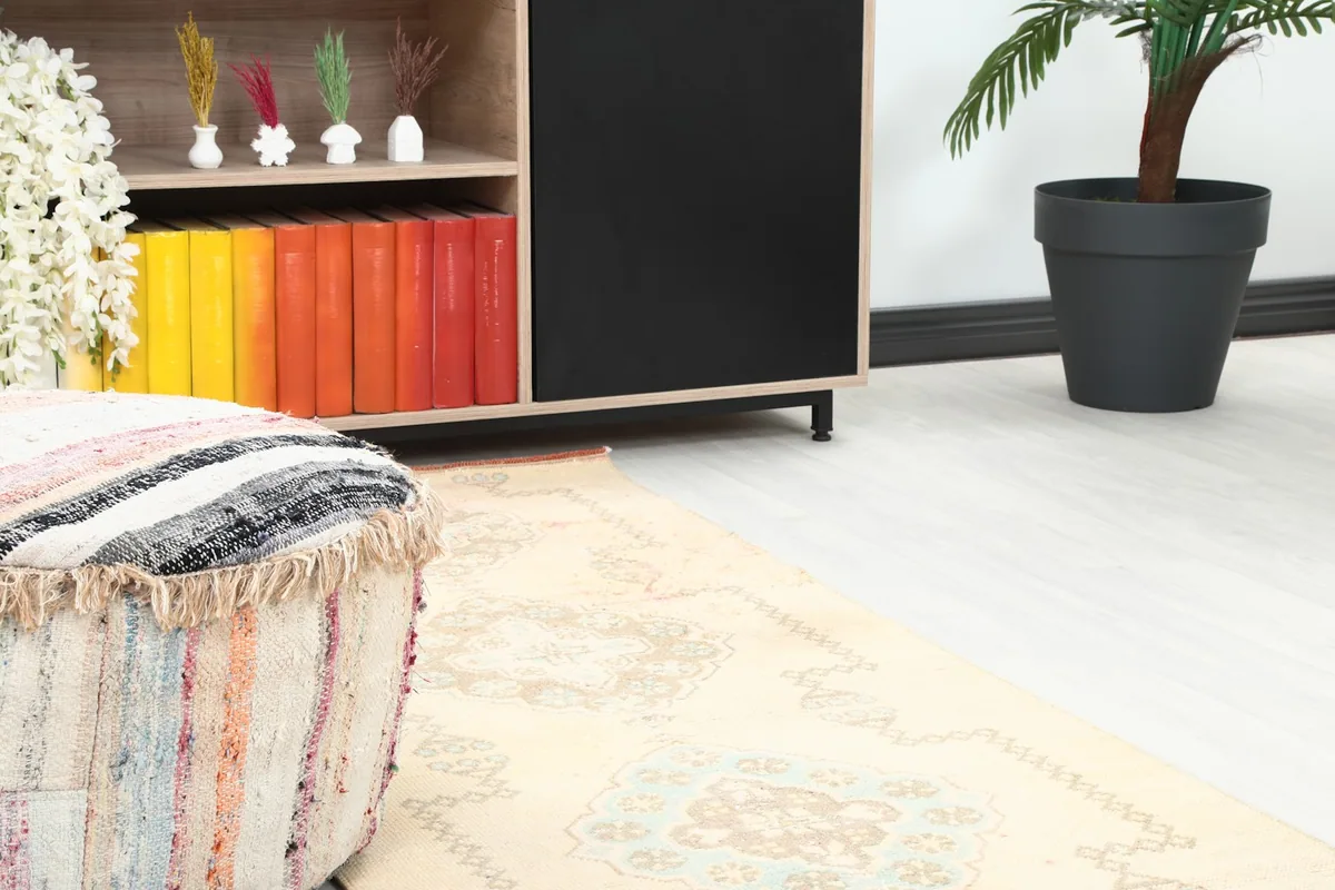 Close-up of one end of the runner rug in a room, showing detail near a pouf and cabinet.