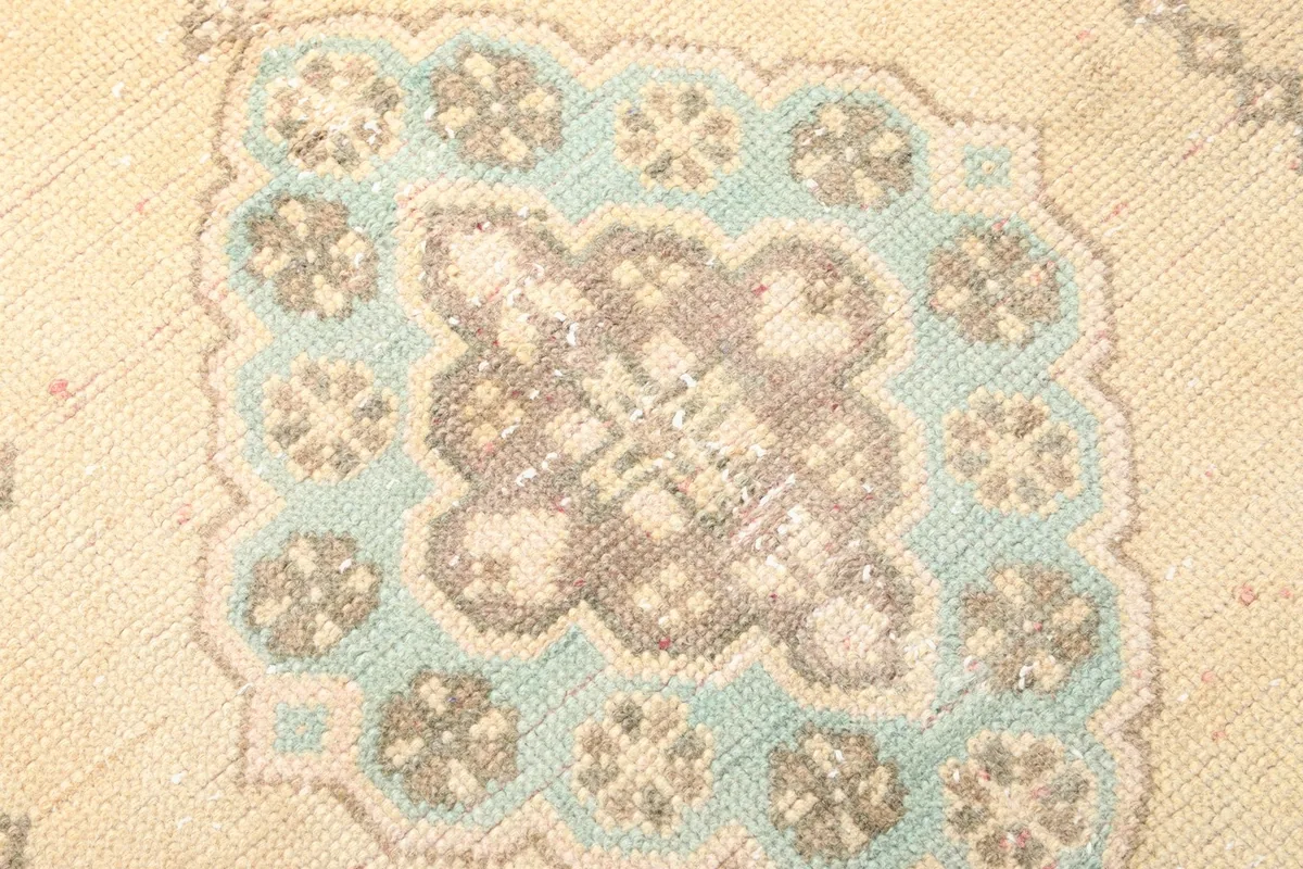 Close-up detail of a central geometric medallion, showing blue and brown colors and intricate knotting.