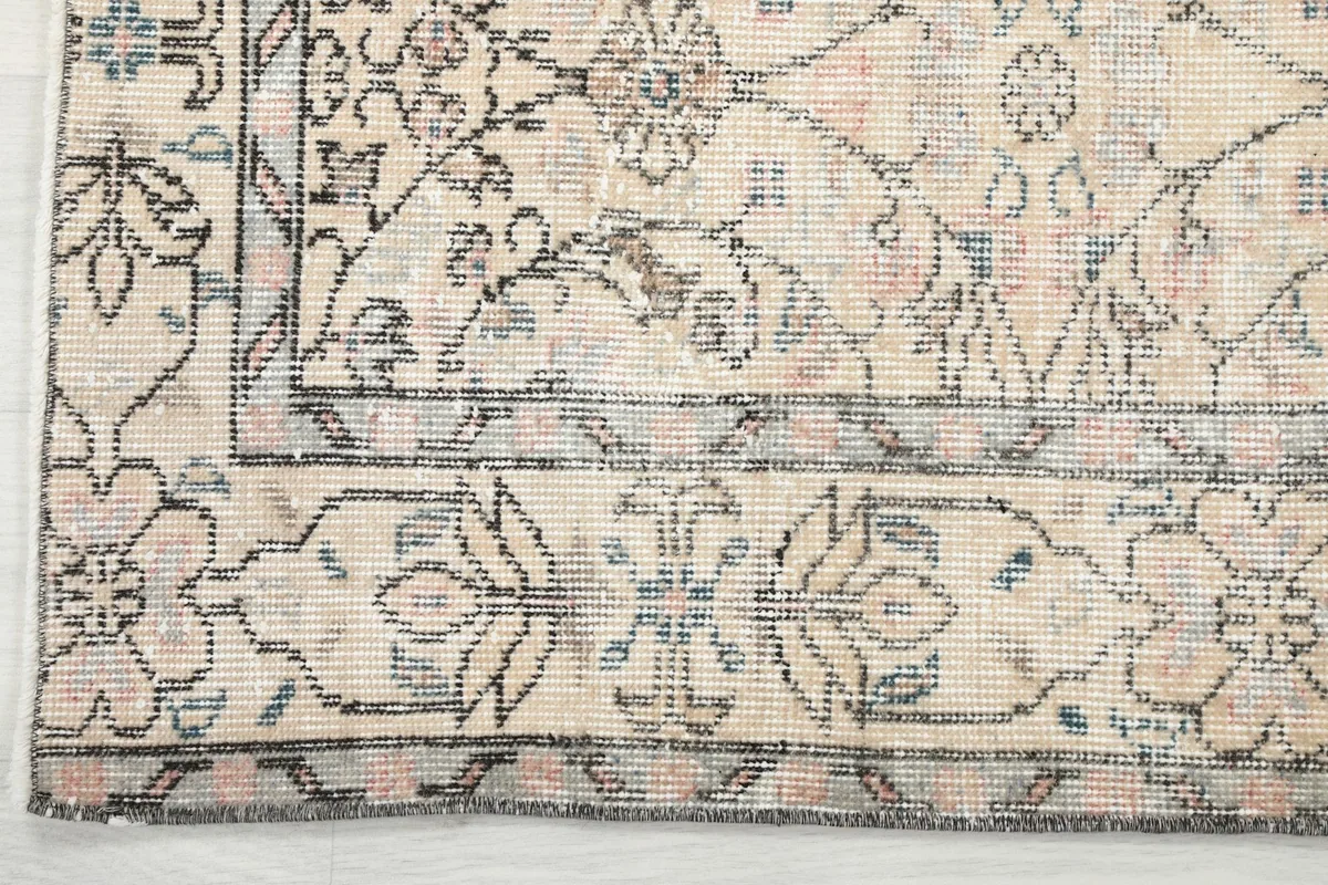 Close-up of the rug's border design, featuring stylized floral elements and a gray outline.