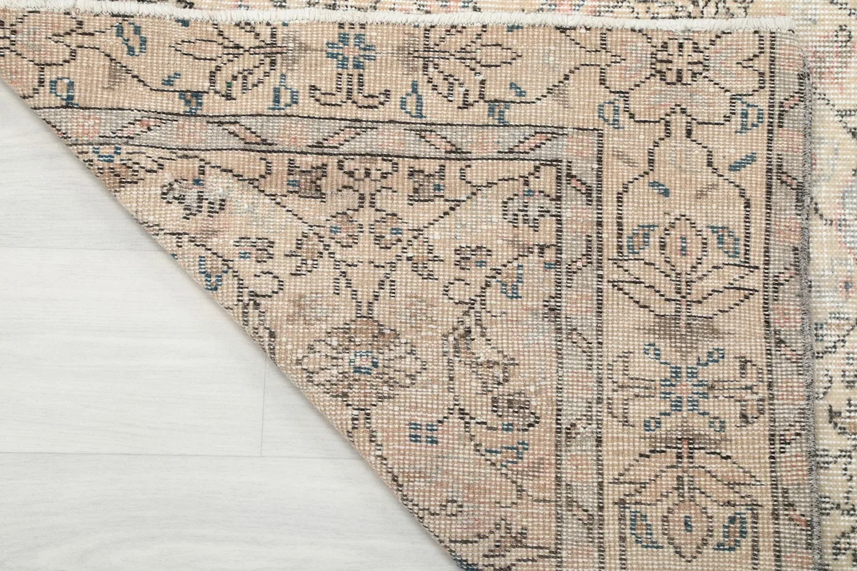 Corner of the rug turned over, revealing the hand-knotted wool pile and cotton foundation structure.