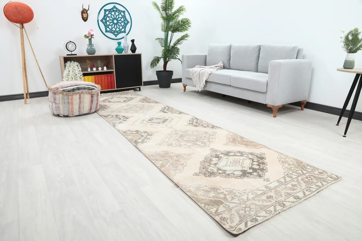 Angle view of the cream and beige runner rug in a room, highlighting its neutral tones and long shape