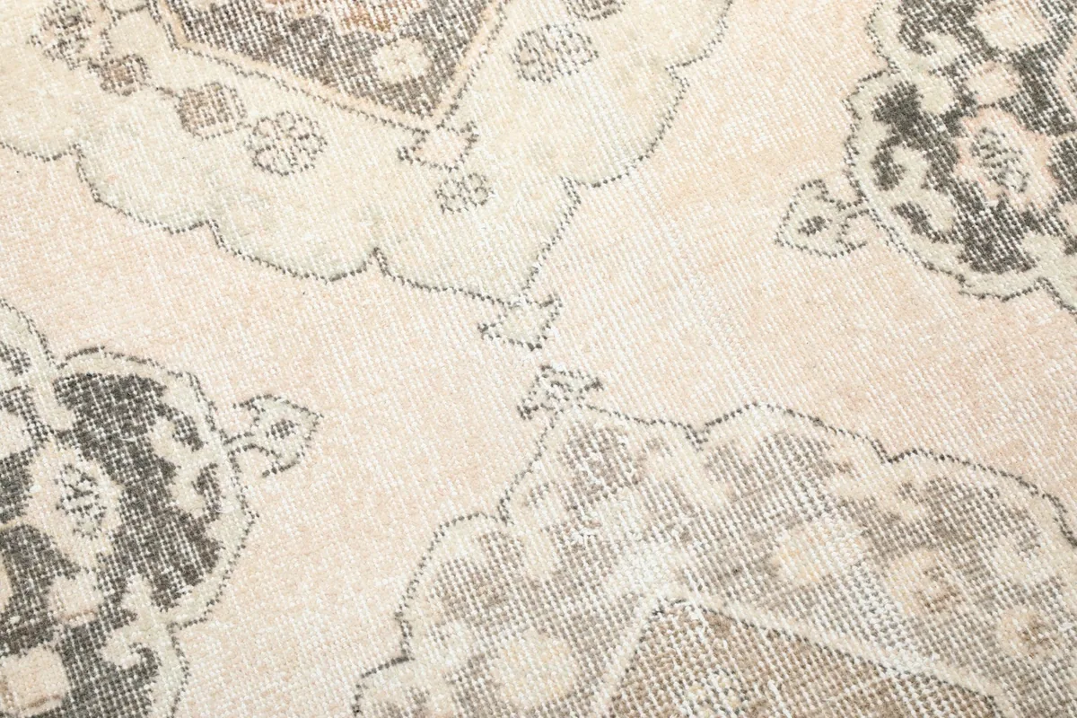 Detailed view of the rug's faded geometric patterns and the light cream background