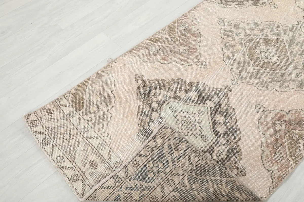 Corner of the runner rug folded back, showing the wool pile surface and the cotton foundation