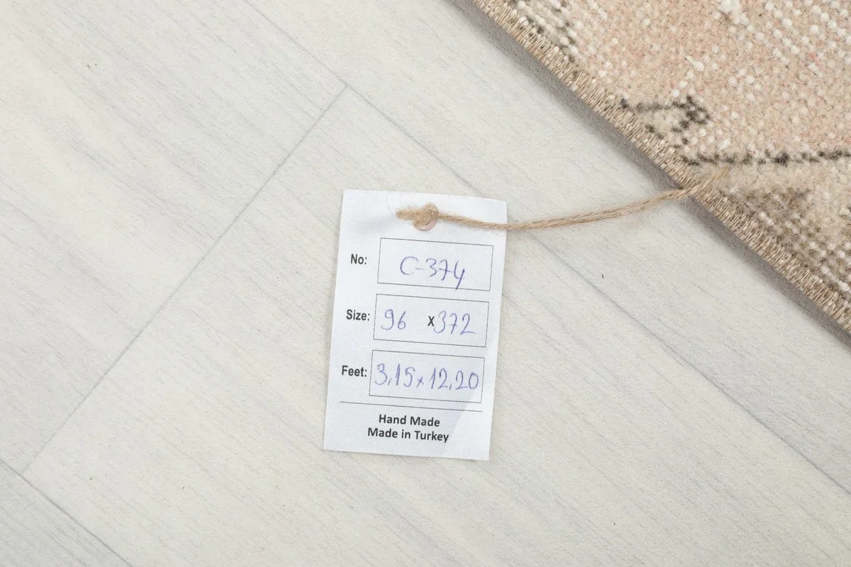 Tag displaying the rug's dimensions in centimeters and feet, confirming it is hand-made in Turkey