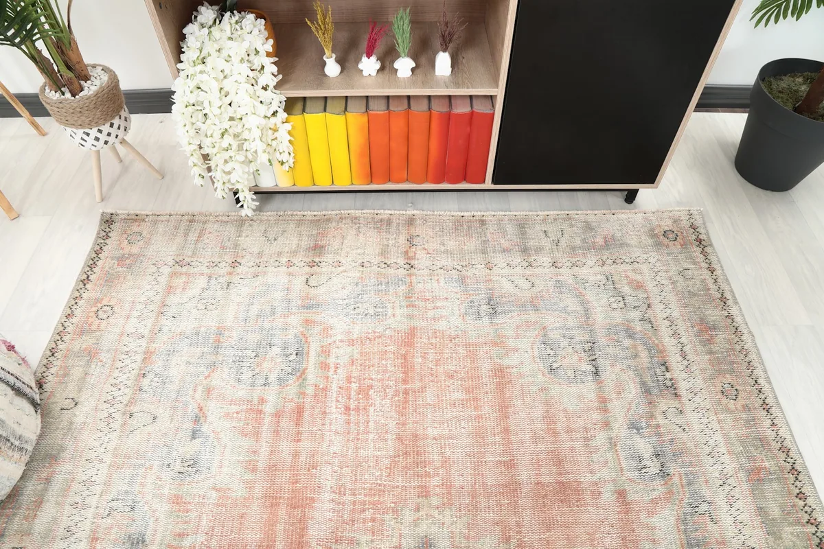 Diagonal view of the rose and beige area rug, highlighting the distressed texture and motifs