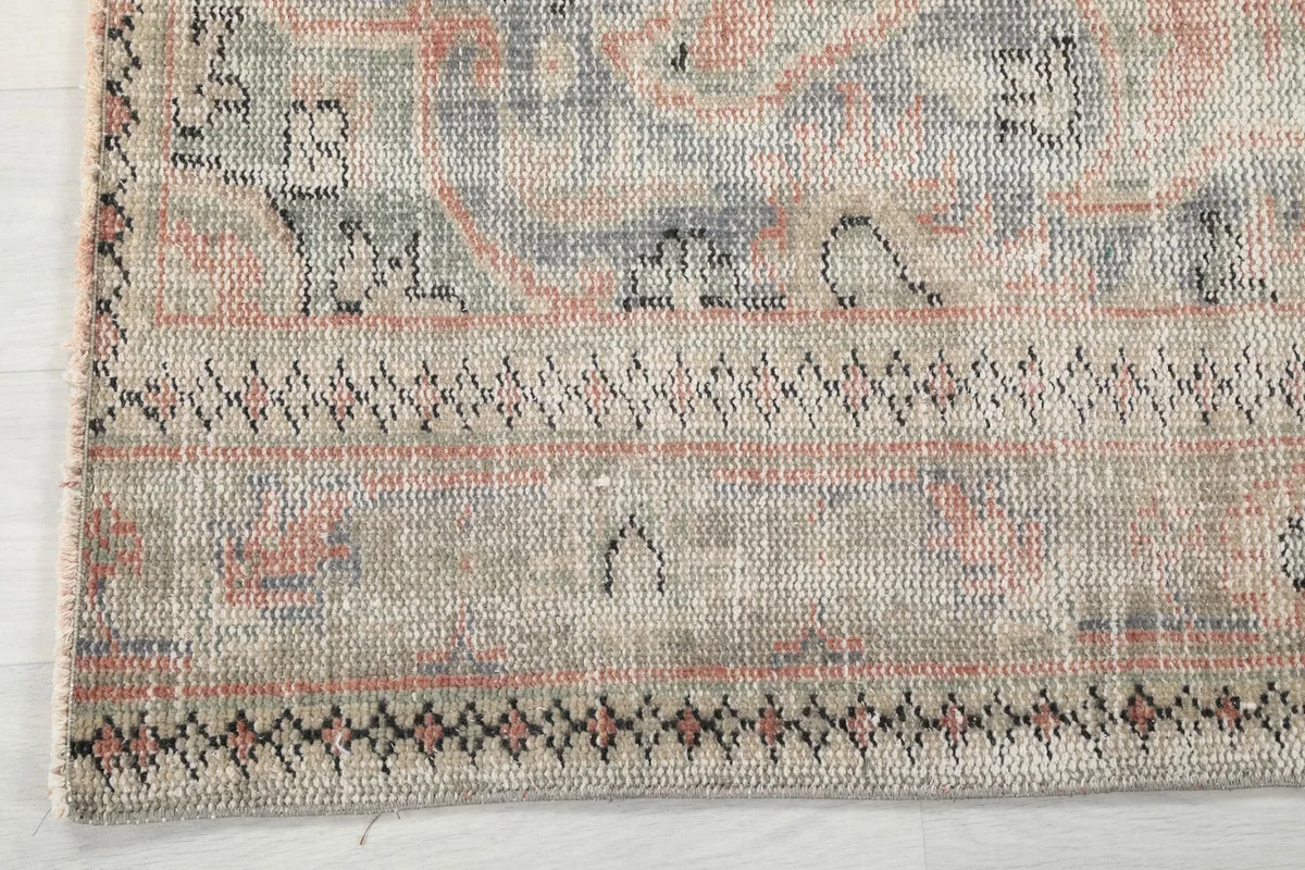 Close-up of the geometric border design on the vintage wool rug, featuring beige and blue details