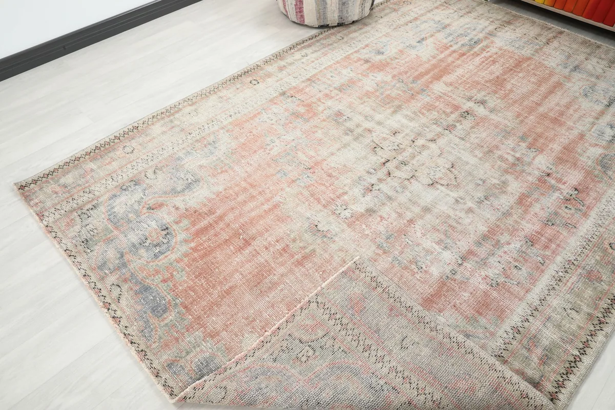Corner of the vintage rose and beige rug folded to show the thickness and texture of the wool pile