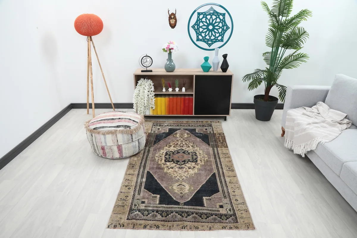 Vintage Anatolian rug with rose and navy medallion in a modern living room setting with a light sofa and decor.