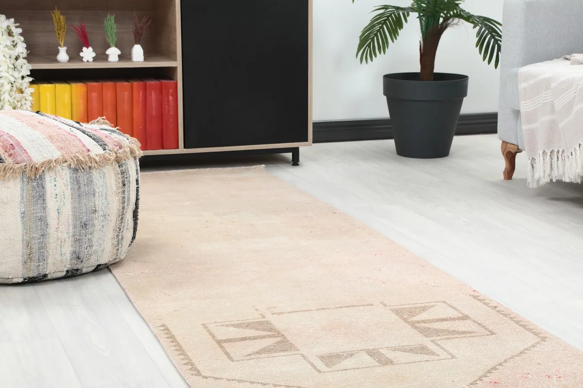 Close-up view of the rug's pattern and texture, showing it extending towards a decorative pouf.