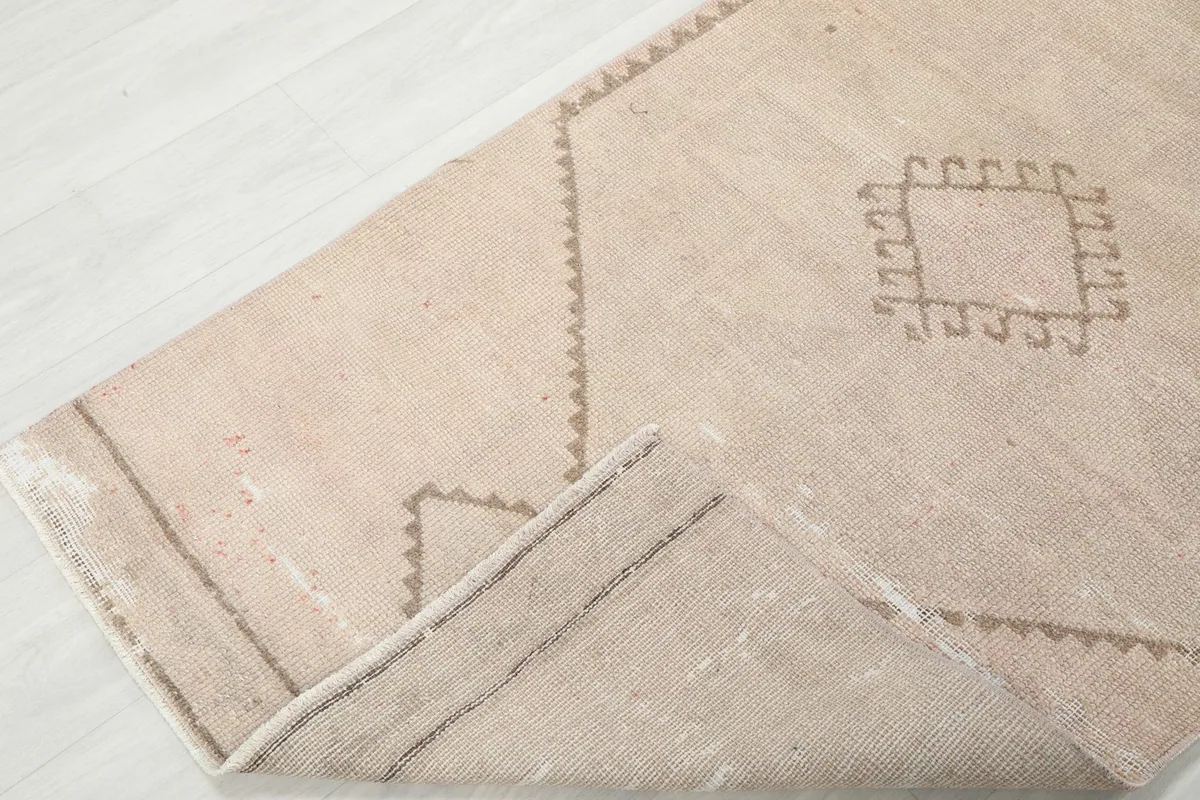 Corner of the runner rug folded back, showing the thickness and construction from the top side.