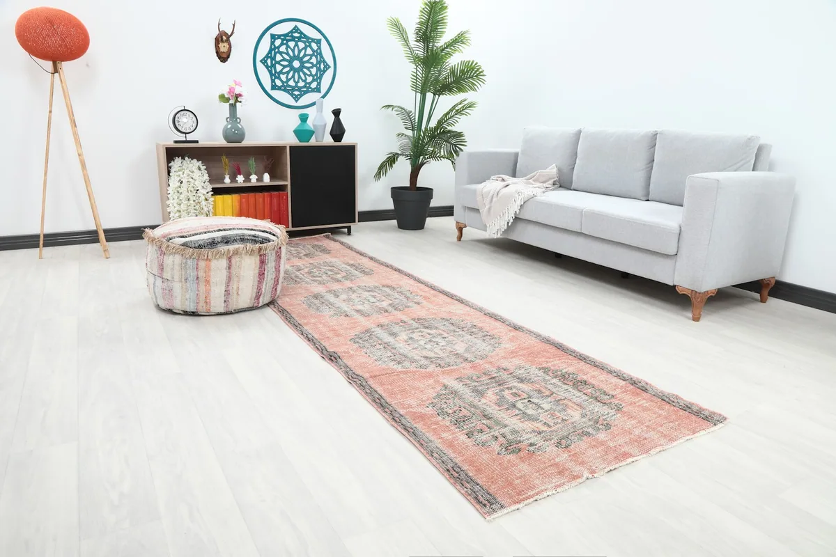Angle view of the rose and gray runner rug in a living space, highlighting its faded colors.