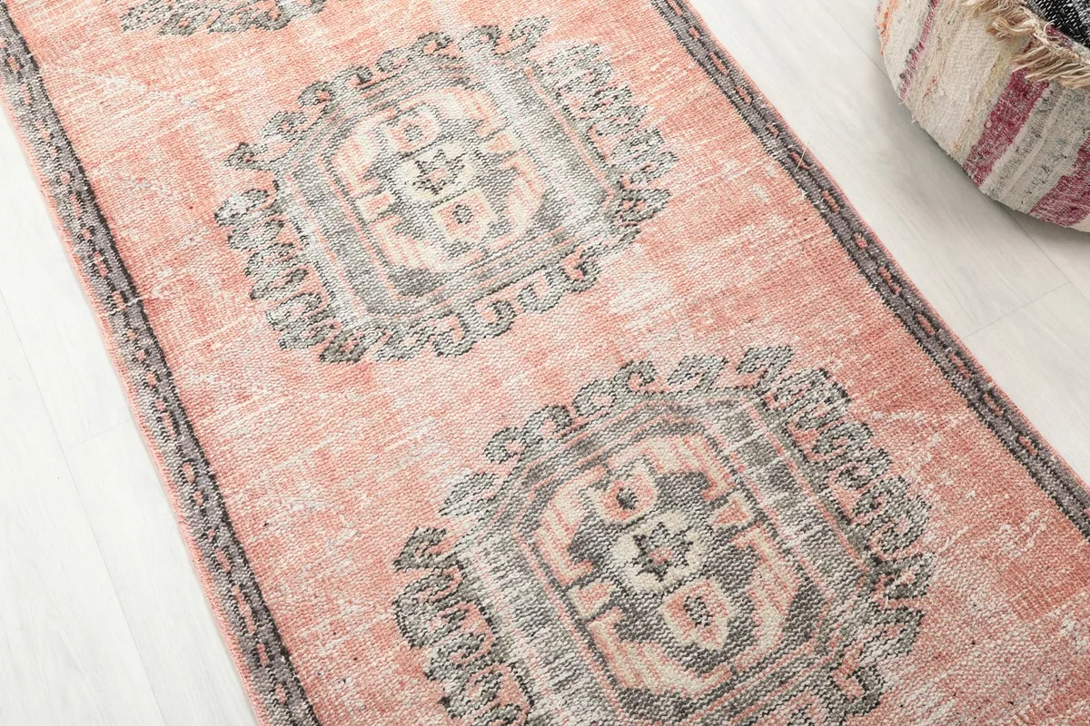 Detailed view of the rose field and a gray geometric medallion, showing the vintage patina.