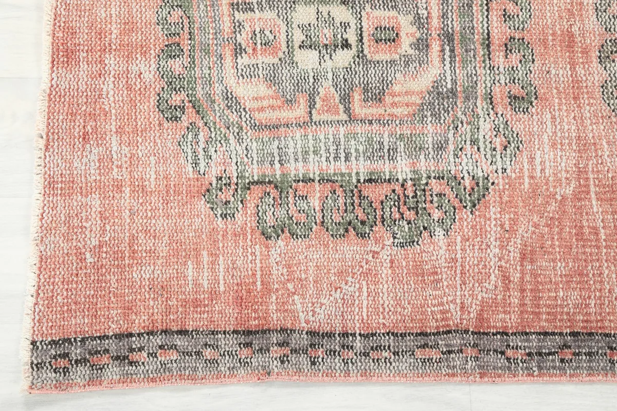 View of the rug's border and fringe, showing subtle wear consistent with its vintage age.