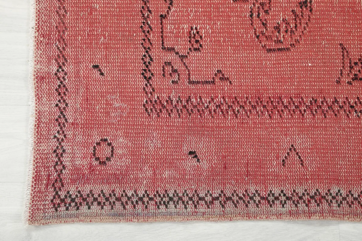 Corner detail of the rose rug, showing the outer border design and slight wear