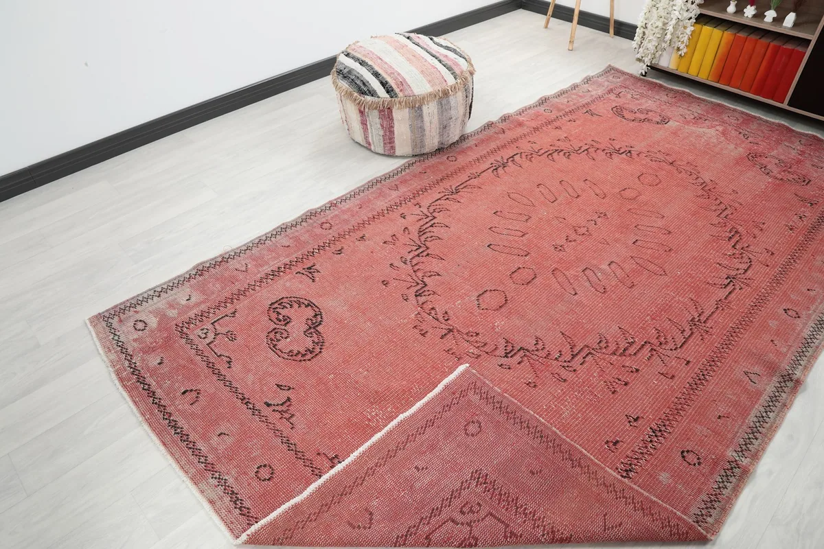 Angle view of the rose rug with a corner folded back, showing the cotton foundation