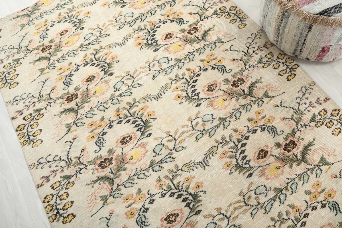 Detailed view of the rug's vintage wool pile and intricate floral patterns in pink, yellow, and green