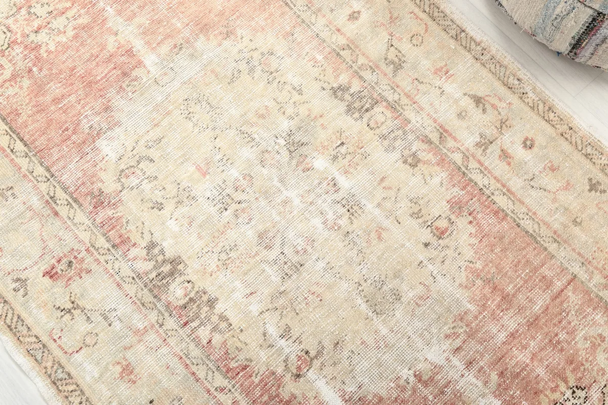 Detailed view of the rug's central design, highlighting the faded rose tones and beige accents.