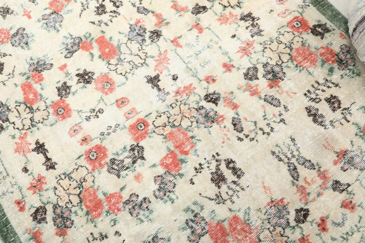 Detailed view of the ivory field with rose and black floral motifs and natural wear.