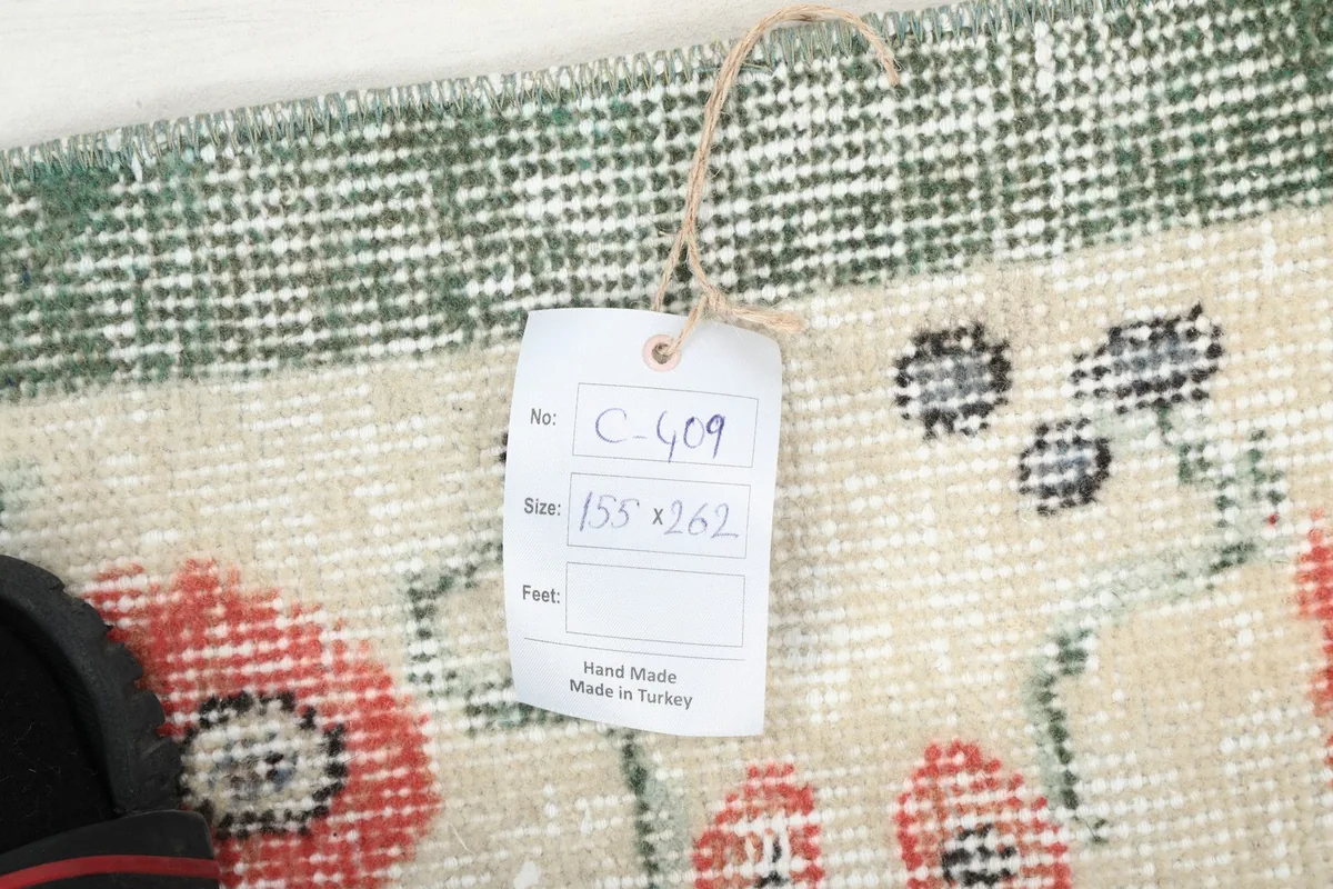 Tag showing the rug's dimensions (155 x 262 cm) and origin, next to the rug pile.
