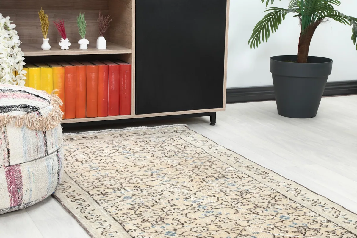 Close-up of the beige rug's floral pattern and border next to a wooden cabinet