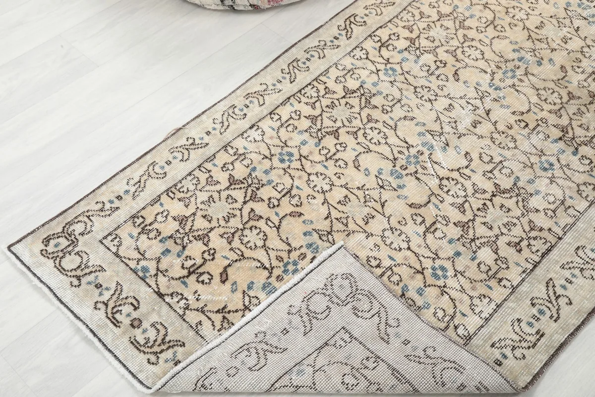 Corner of the rug folded back to show the cotton foundation and hand-knotted construction