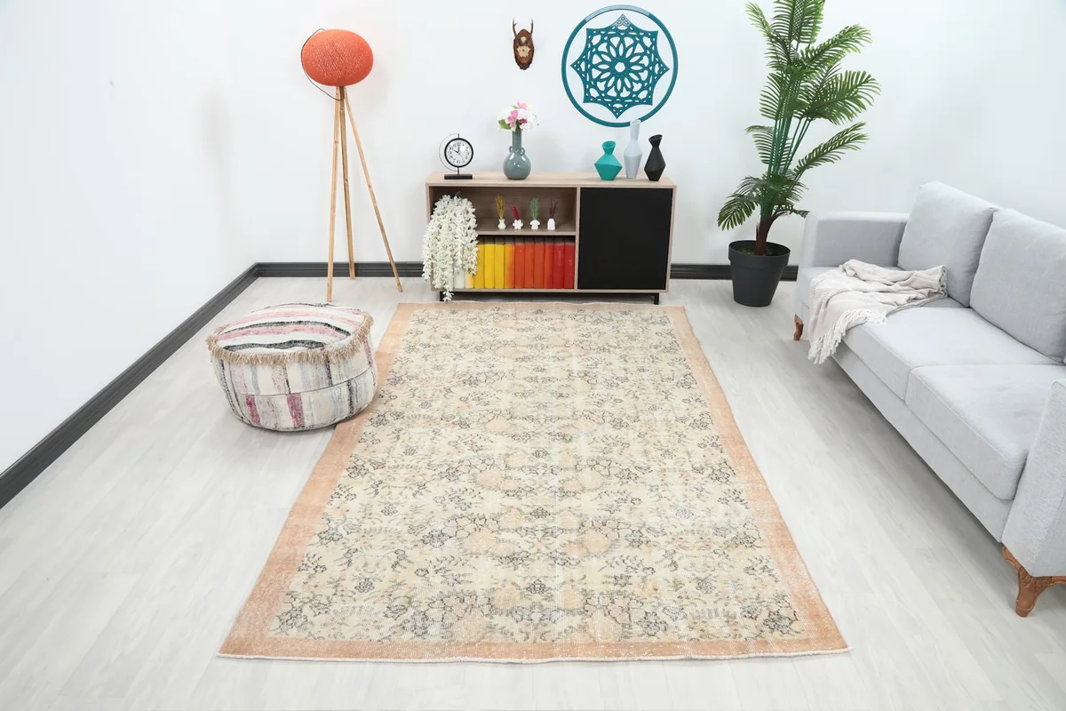 Vintage cream floral rug displayed in a bright living room with a gray sofa