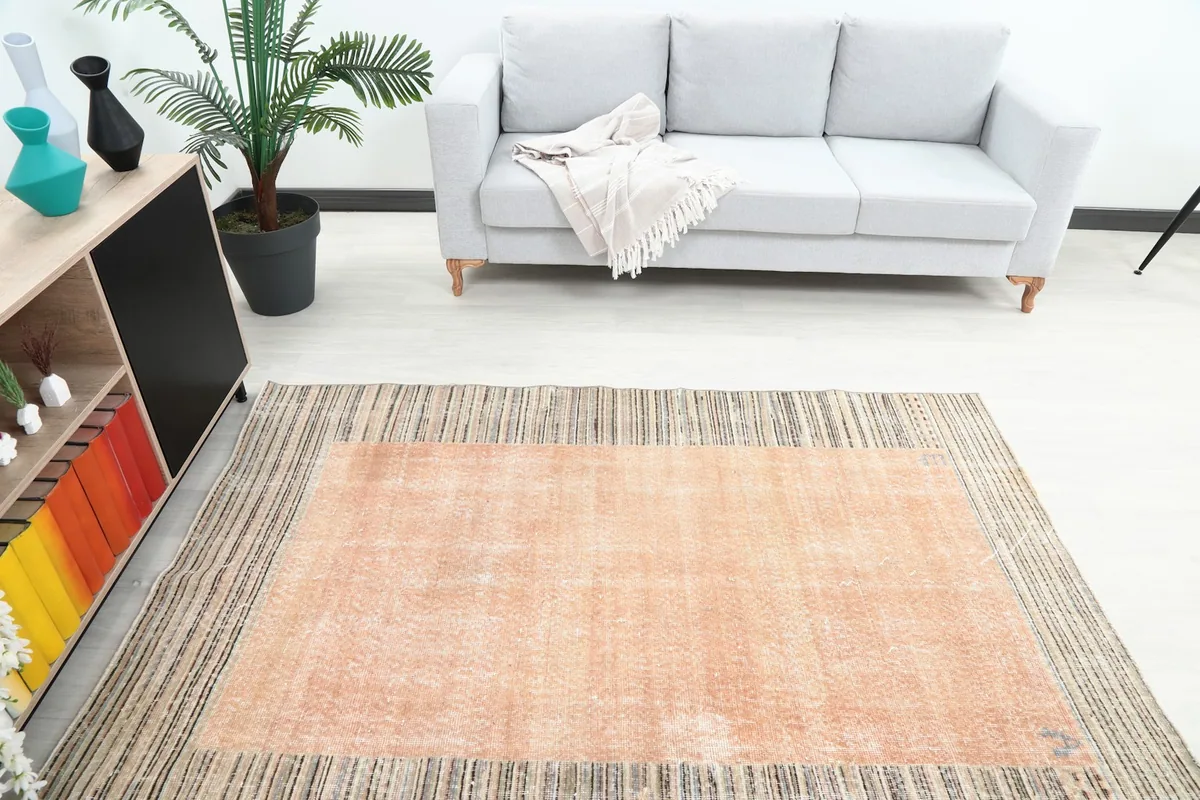 Overhead view of the vintage rust and beige striped rug in a modern living room with a sofa.