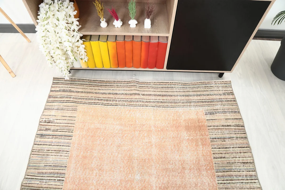 Top-down view of the rust rug in a room, highlighting the distressed texture of the main field.