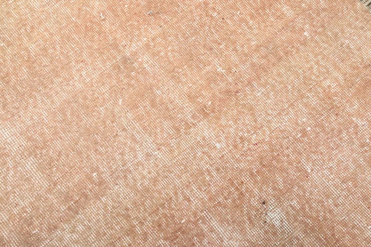 Detailed close-up of the rust colored pile and distressed surface of the hand-knotted rug.