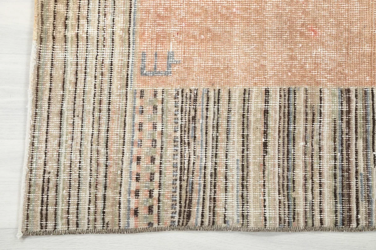 Close-up of the striped beige and charcoal border detail and corner of the vintage Anatolian rug.