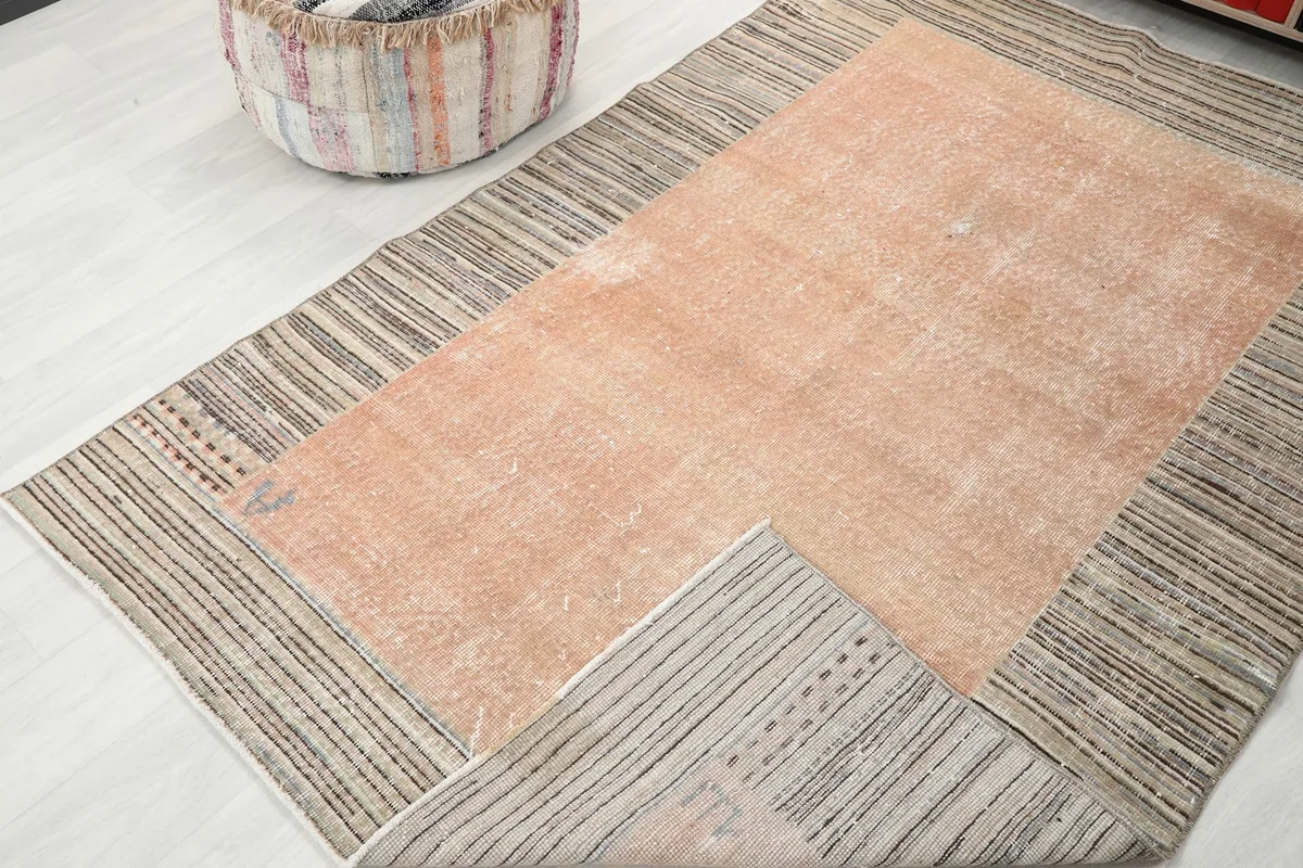 View of the rust rug with a corner folded over, showing the underside and construction.