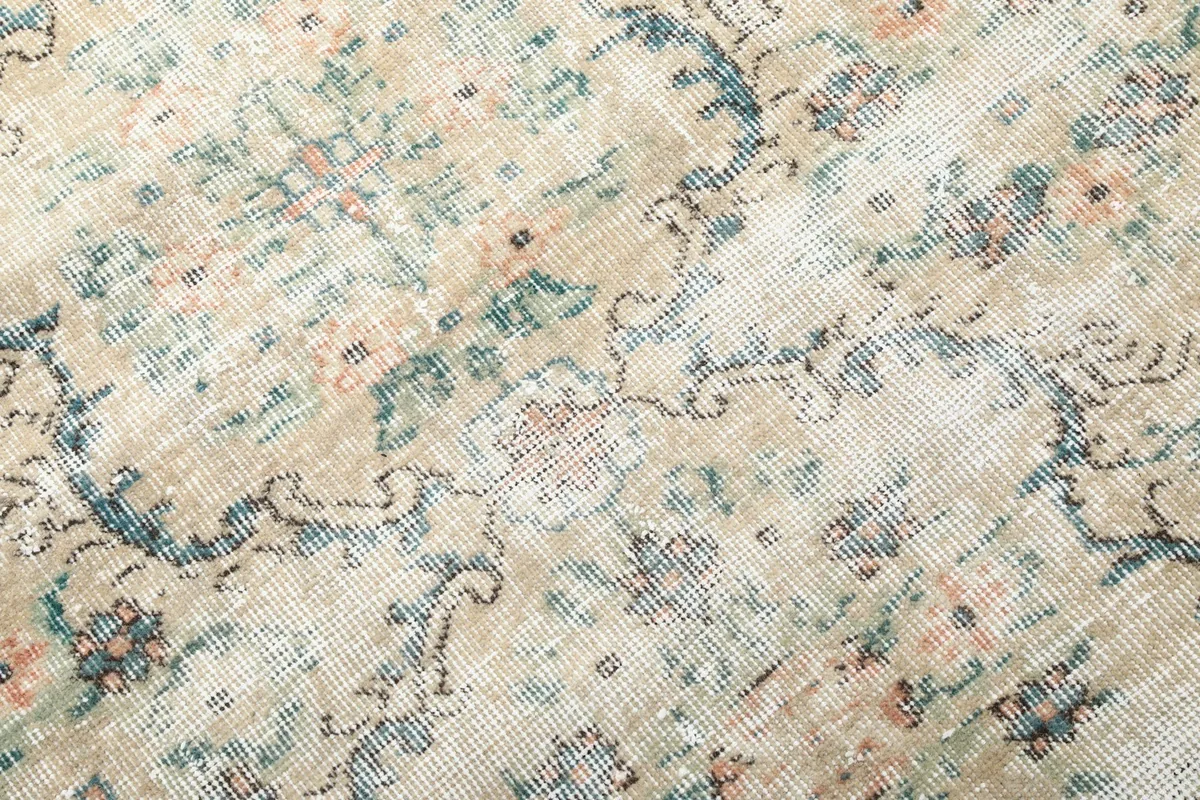 Macro detail of the hand-knotted wool pile, revealing blue, green, and rose tones in the pattern