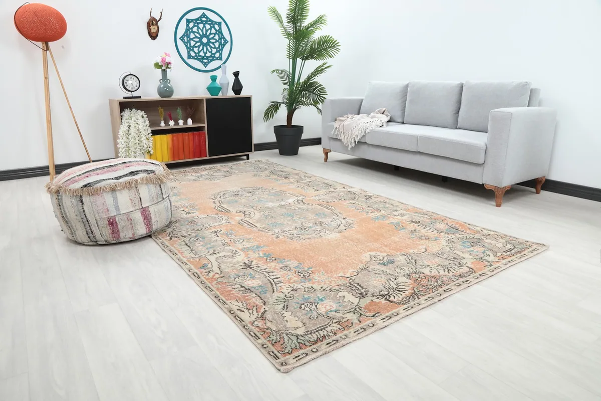 Angle view of the rust floral medallion rug in a living space with a gray sofa