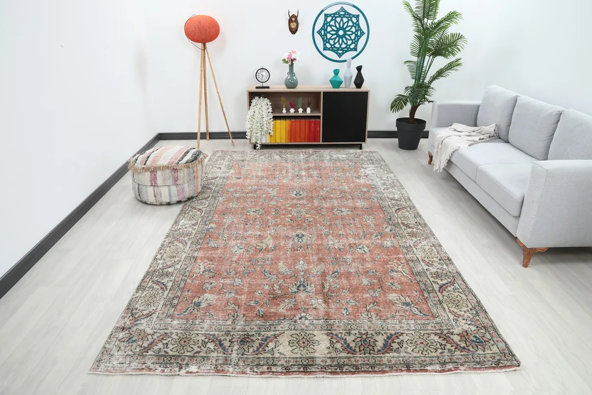 Large vintage rust floral Anatolian rug displayed in a modern living room setting with a gray sofa.