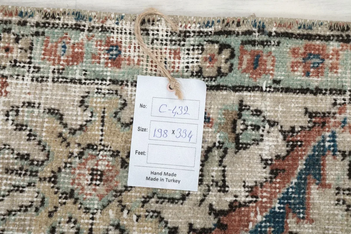 Close-up of the rug's corner with a tag showing the dimensions 198 x 334 cm, confirming hand-made origin.