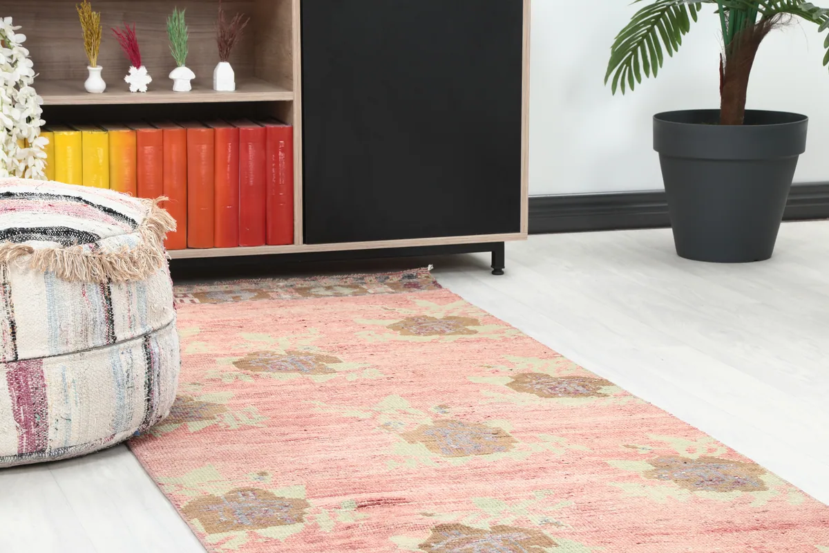 Close-up of the Faded Rose Floral Anatolian Runner in a room, showing the end of the rug near furniture.