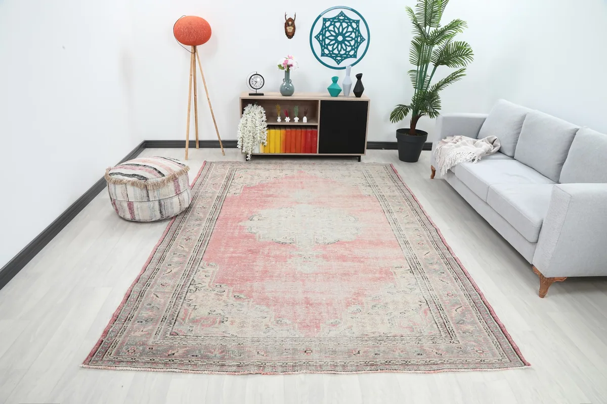 Vintage rose and gray rug displayed in a modern living room setting with light furniture.